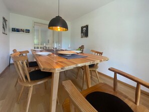 A dining area with a wooden table, six chairs, and a black pendant light. - Holiday Apartment Lucky guy (Oberstaufen)
