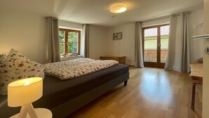 A bedroom with a bed, a bedside table with a lamp, a window, and a balcony. - Holiday Apartment Lucky guy (Oberstaufen)