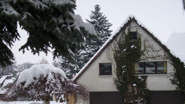 A house with a snow-covered roof and a garage door. - Apartment at the Knappensee in Gross Sarchen (Ebersbach-Neugersdorf)