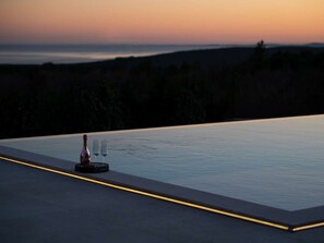 A rooftop pool with a sunset view, a bottle, and two glasses.