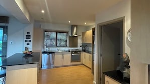 Una cocina moderna con piso de madera, electrodomésticos de acero inoxidable y una isla central.