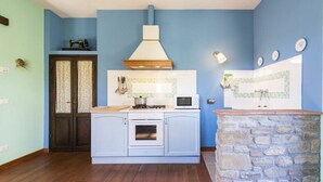 Una cocina con una isla de piedra, estufa, microondas y una lámpara colgante.