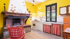 Una cocina con chimenea, una zona de comedor con mantel a cuadros rojo y blanco, y una pared amarilla.