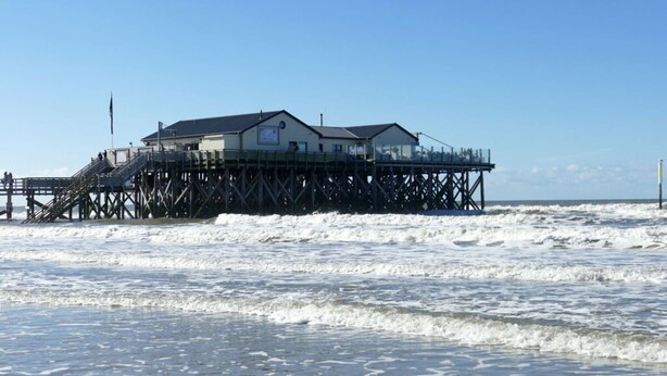 A pier with a building on stilts, featuring a staircase leading to the entrance. - Kille Family - Attic (St. Peter-Ording)