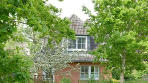 A two-story house with a brick facade, a dormer window, and a visible balcony. - Kille Family - Attic (St. Peter-Ording)