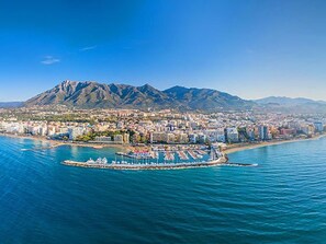 A coastal cityscape with a marina, buildings, and a mountain in the background.