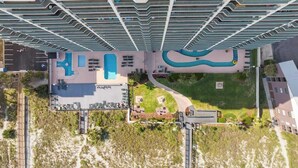 A high-rise hotel with multiple balconies, a swimming pool, and a landscaped area. - Luxury Oceanfront 3Bedroom Paradise (North Myrtle Beach)