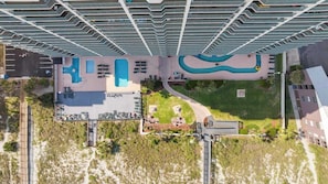Ett högt hotell med flera balkonger, en swimmingpool och ett välanlagt område.