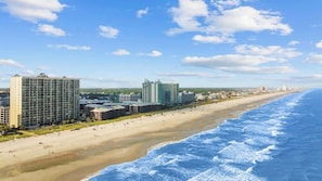Un hôtel situé sur la côte, composé de plusieurs immeubles de grande hauteur, avec une plage de sable et un accès à l’océan.