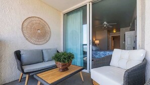 A balcony with a sofa, a small table, and a wicker chair. - Luxury Oceanfront 3Bedroom Paradise (North Myrtle Beach)