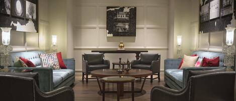 Un salón amplio con dos sofás, una mesa redonda de centro y dos sillones. Un cuadro grande cuelga de la pared sobre la mesa.