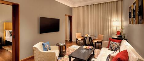 A modern living room with a sofa, armchairs, a coffee table, and a flat-screen TV.