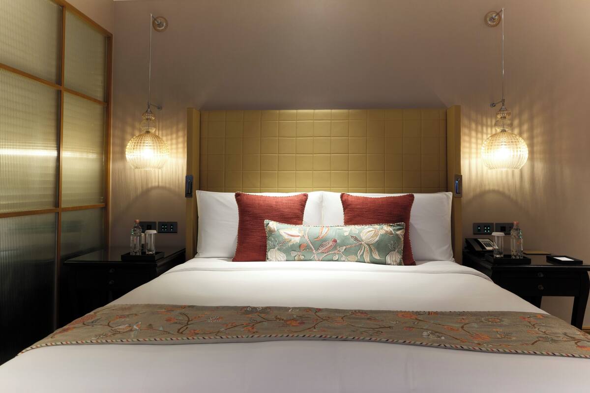 Habitación de hotel con una cama grande, dos mesitas de noche, una lámpara y un teléfono.