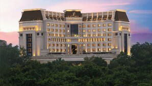 A large, multi-story hotel with a prominent entrance and a sign reading "The Leela."