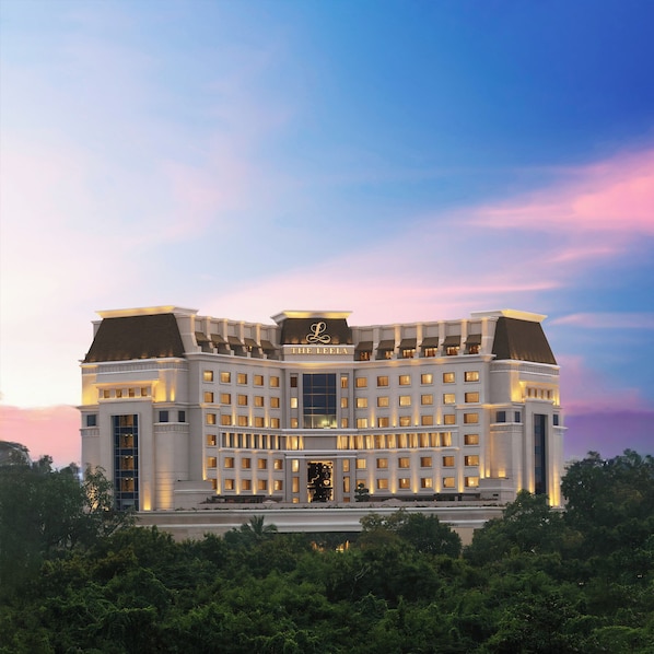 A large, multi-story hotel with a prominent entrance and a sign reading "The Leela."