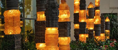 A series of intricately carved stone pillars with warm lighting, surrounded by lush greenery.