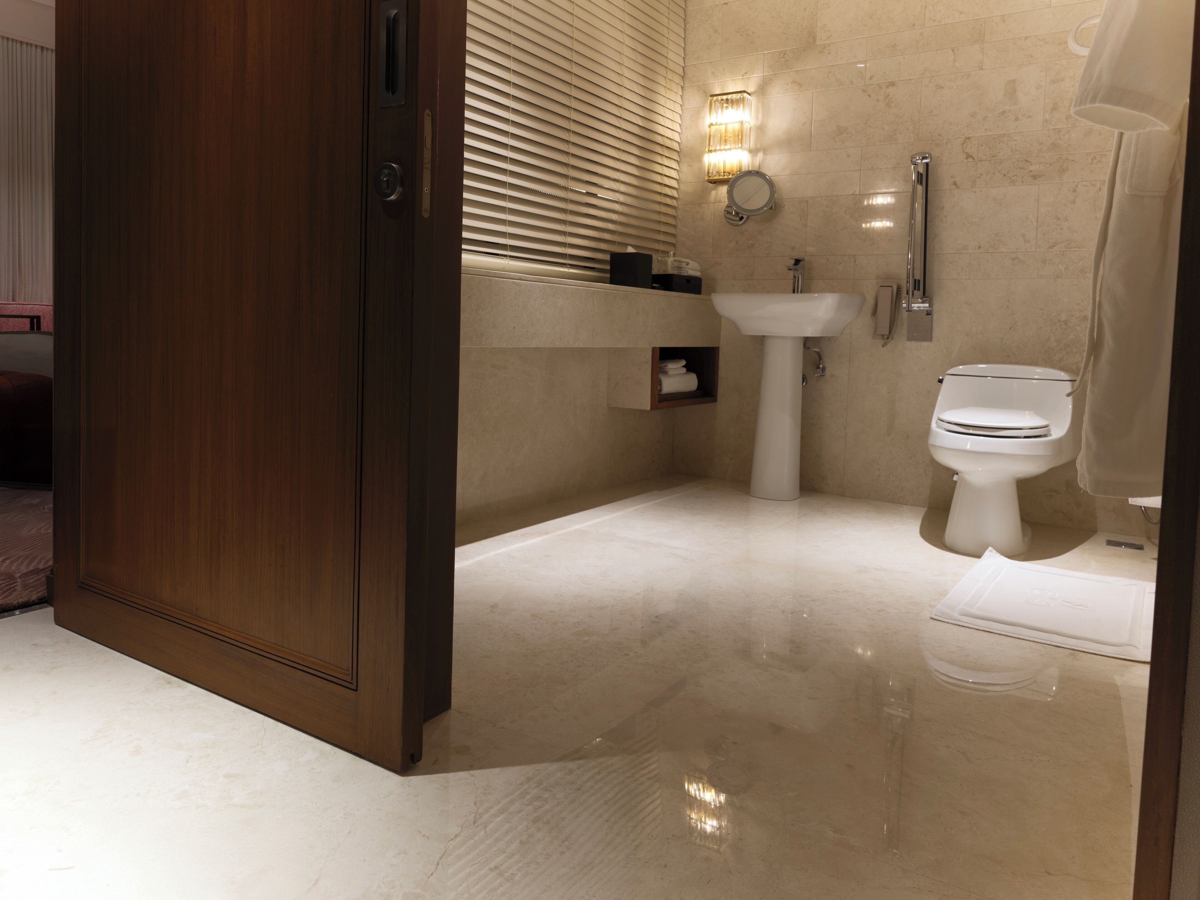 A modern bathroom with a wooden door, a sink, a toilet, and a mirror.