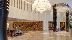 A spacious lobby with a large chandelier, a wall of colorful photographs, and a polished marble floor. - The Leela Hyderabad Banjara Hills (Hyderabad)
