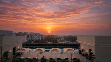 Terraza en la azotea con vistas al atardecer, mobiliario exterior y una piscina.