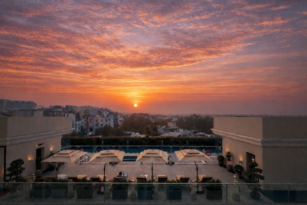 Terraza en la azotea con vistas al atardecer, mobiliario exterior y una piscina.