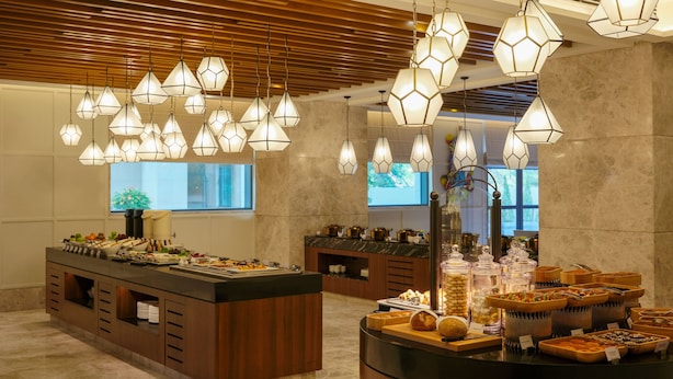 A buffet area with multiple food stations, wooden paneling, and hanging pendant lights.