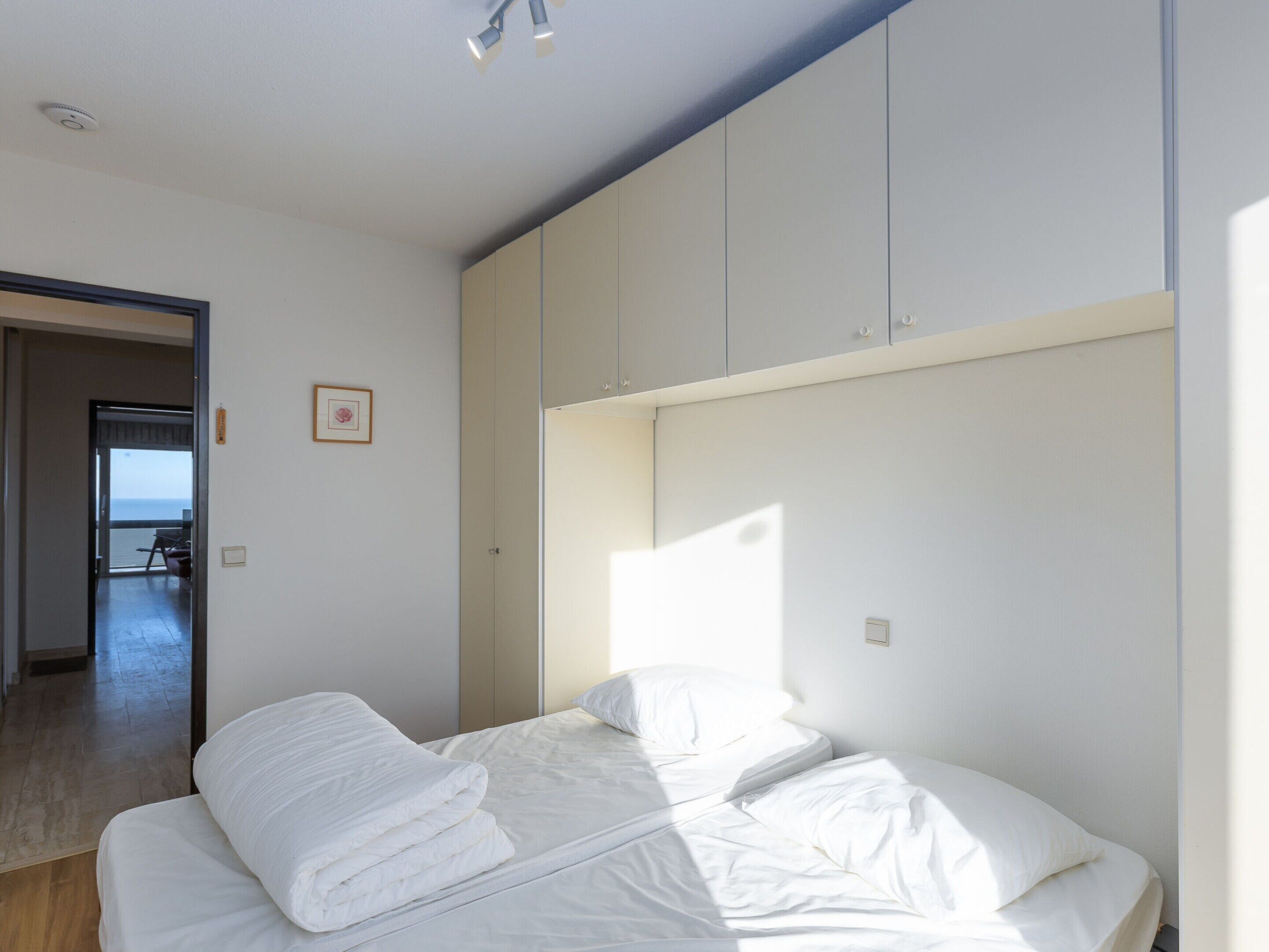 A bedroom with a bed, a wardrobe, and a door leading to a balcony.