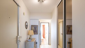 A hallway with a door on the left, a small table with a lamp, and a painting on the wall. - Bright Apartment on the 7th Floor (Middelkerke)