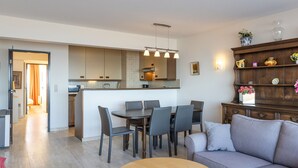 A modern living room with a grey sofa, a wooden coffee table, and a dining area with a table and chairs. - Bright Apartment on the 7th Floor (Middelkerke)