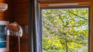 A room with a large window, wooden walls, and a lamp. - Lodge 4 Hot Tub by Interhome (Launceston)