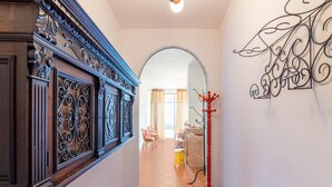 A hallway with a wooden door, a red coat rack, and a decorative wall piece. - Belvilla by OYO Casa Castiglia (Polino)