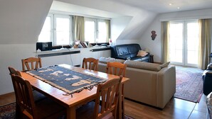 A modern loft apartment with a dining area, a sofa, and a kitchen. - Ter Streep 0201 Apartment Near the Beach (De Haan)