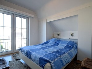 Et soveværelse med en seng, et vindue og en lampe monteret på væggen.