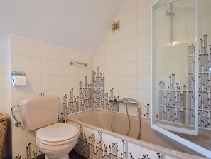 Et badeværelse med toilet, badekar og bruser.