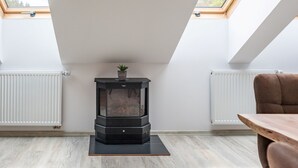 A modern room with a wood-burning stove, skylights, and a dining area. - Miner's Lodge & Sauna by Interhome (Jachymov)