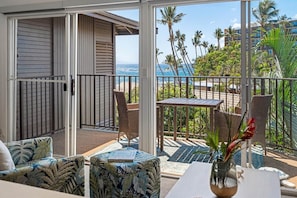 Ein Balkon mit Blick auf das Meer, ein Tisch mit einer Vase und ein Stuhl.