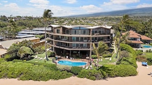 Un edificio de varios pisos con piscina, rodeado de vegetación y vistas al paisaje.