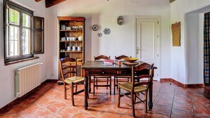 Un coin repas avec une table en bois, des chaises, une bibliothèque et un radiateur.
