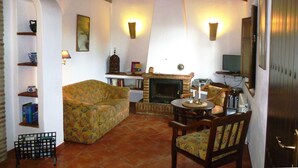 Un salon confortable avec un canapé, des fauteuils, une cheminée et un téléviseur.