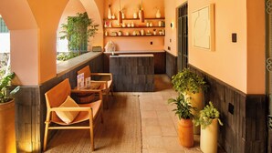 A reception area with a wooden reception desk, seating area with chairs, potted plants, and a tiled floor. - Hotel Libertad 1416 (Guadalajara)