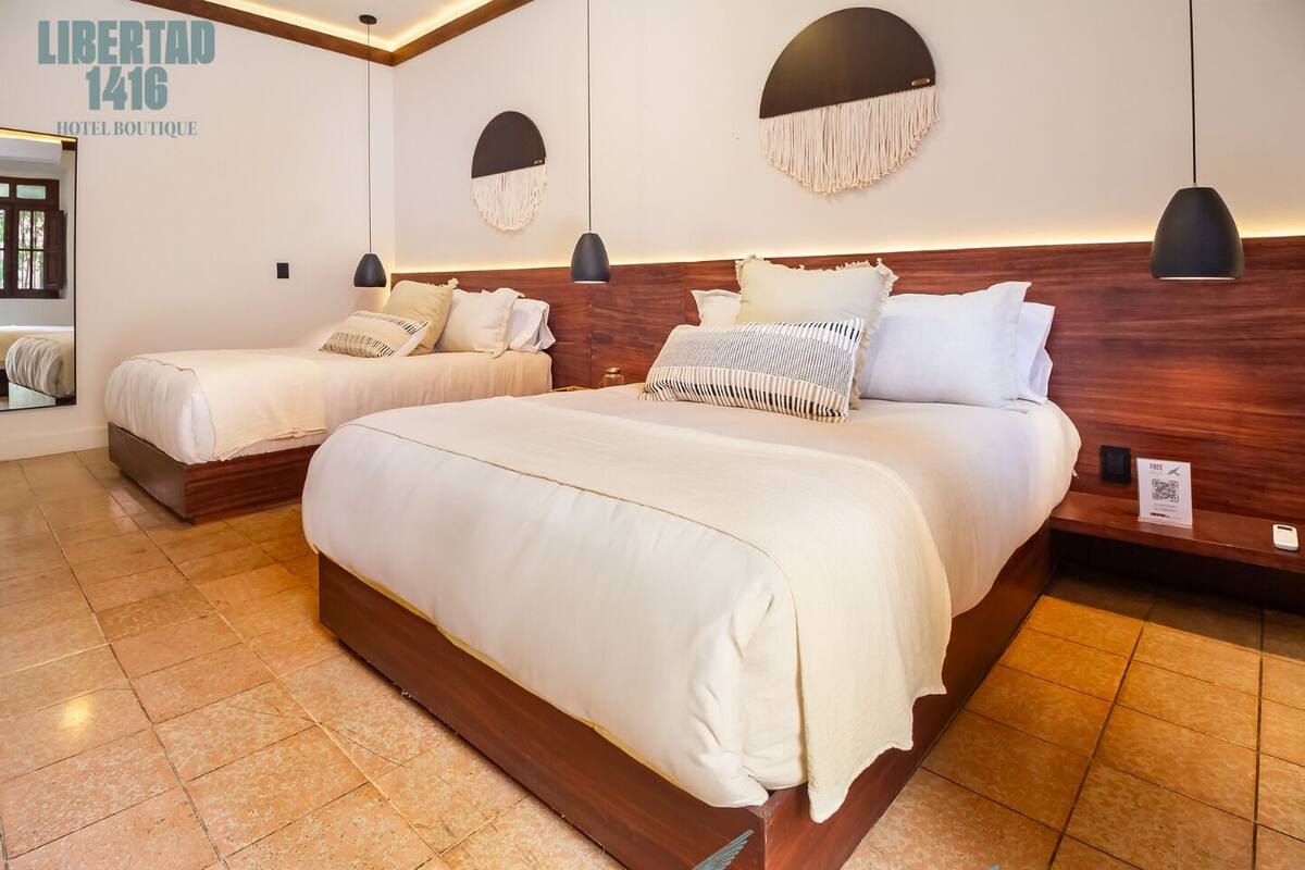 Een hotelkamer met twee bedden, een houten hoofdeinde en een grote spiegel.