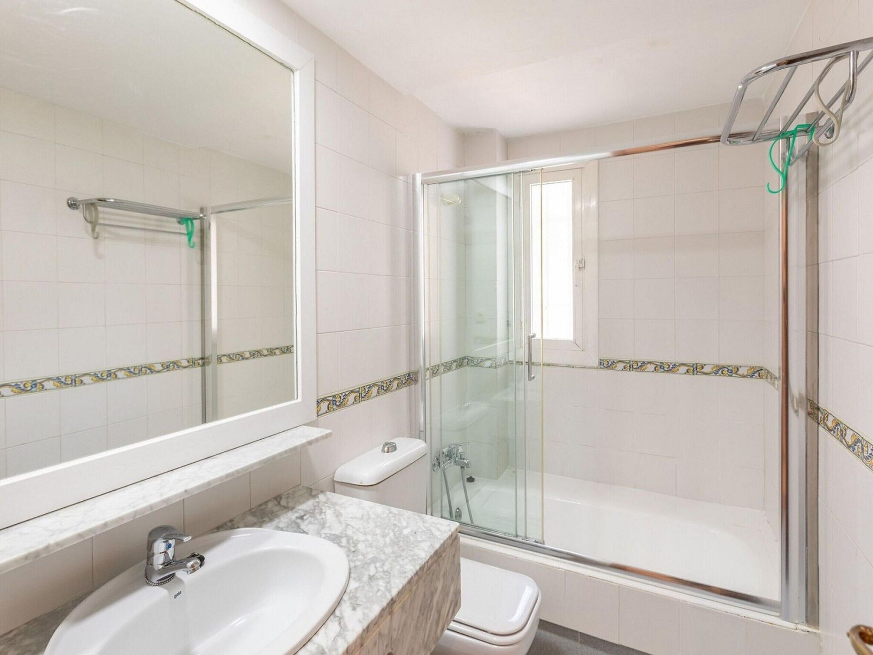 Un baño con lavamanos de mármol, cabina de ducha de vidrio y un inodoro.