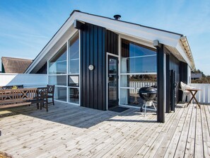 A modern house with a large deck, a barbecue grill, and a wooden bench. - 9 Person Holiday Home in Harboore (Harboore)