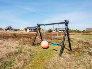 A swing set in a grassy field with houses in the background. - 9 Person Holiday Home in Harboore (Harboore)