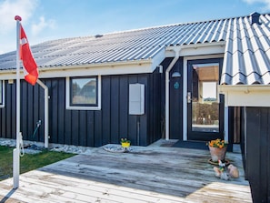 A single-story building with a dark exterior, a tiled roof, and a wooden deck. - 9 Person Holiday Home in Harboore (Harboore)