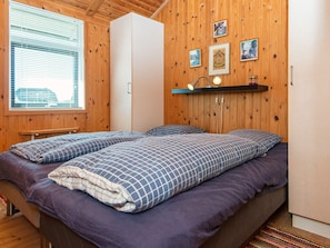 A bedroom with a bed, wooden walls, a window, and a shelf with pictures. - 9 Person Holiday Home in Harboore (Harboore)