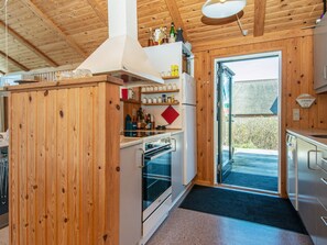 A wooden interior with a kitchen area, including a stove, oven, and shelves with jars. - 9 Person Holiday Home in Harboore (Harboore)