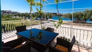 Une terrasse extérieure avec une table et des chaises, une vue sur un plan d’eau et de la verdure.