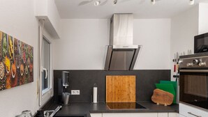 A modern kitchen with a stainless steel range hood, a built-in oven, and a wooden cutting board on the countertop. - Fewo Freiken 28 Comfortable Holiday Residence (Arnsberg)