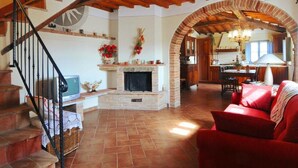 A spacious living area with a fireplace, a red sofa, and a staircase leading to an upper floor. - Elegant Castle Stay With Pool (Foiano della Chiana)