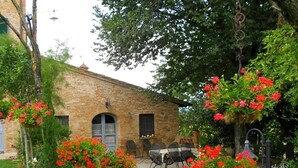 A brick building with a patio area, outdoor seating, and hanging flower baskets. - Elegant Castle Stay With Pool (Foiano della Chiana)